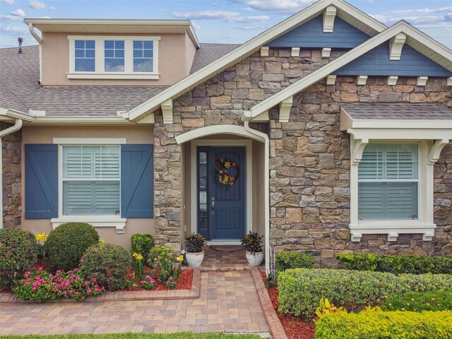 4133 Foxhound Dr, Clermont, FL 34711 - entrance to property with stone siding, a shingled roof, and stucco siding