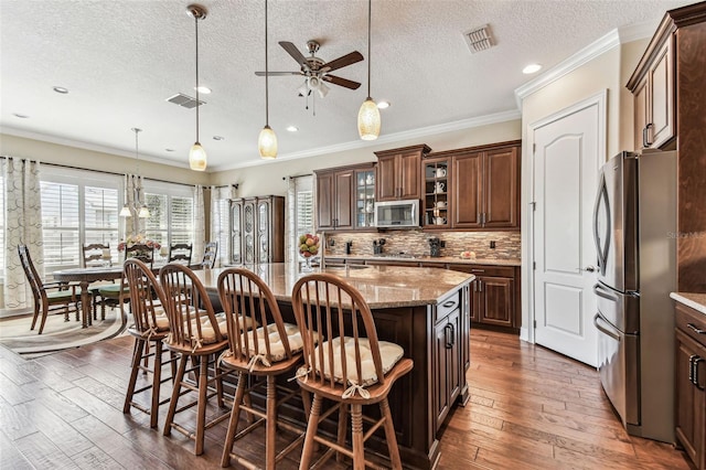 4133 Foxhound Dr, Clermont, FL 34711 - kitchen with appliances with stainless steel finishes, a textured ceiling, a breakfast bar, a ceiling fan, and hardwood / wood-style flooring