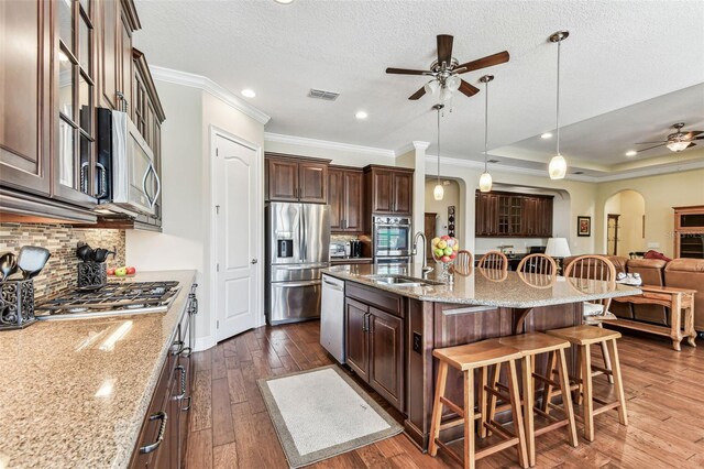 4133 Foxhound Dr, Clermont, FL 34711 - kitchen featuring a ceiling fan, arched walkways, appliances with stainless steel finishes, a breakfast bar, and ornamental molding