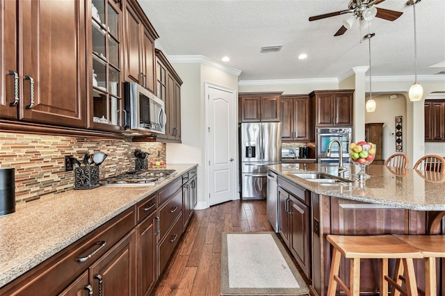 4133 Foxhound Dr, Clermont, FL 34711 - kitchen with stainless steel appliances, a breakfast bar area, ceiling fan, dark wood-style flooring, and light stone countertops
