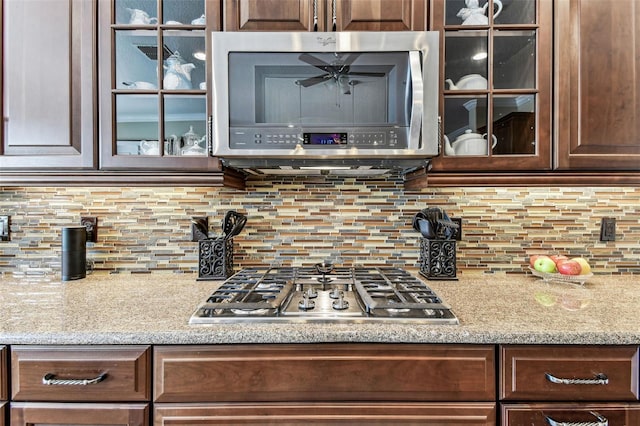 4133 Foxhound Dr, Clermont, FL 34711 - kitchen featuring stainless steel appliances, glass insert cabinets, dark brown cabinets, and backsplash
