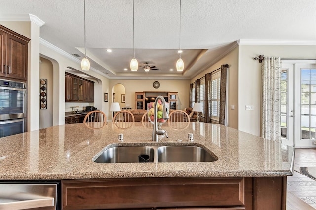 4133 Foxhound Dr, Clermont, FL 34711 - kitchen with arched walkways, a center island with sink, plenty of natural light, ornamental molding, and a raised ceiling