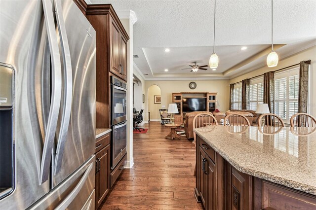 4133 Foxhound Dr, Clermont, FL 34711 - kitchen with stainless steel appliances, a tray ceiling, ornamental molding, dark wood-type flooring, and pendant lighting