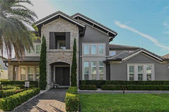 7550 John Hancock Dr, Winter Garden, FL 34787 - view of front facade with stone siding, stucco siding, a tile roof, and a front yard