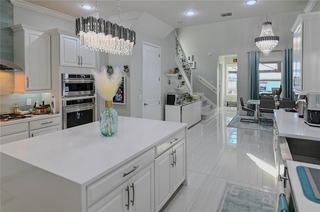 7550 John Hancock Dr, Winter Garden, FL 34787 - kitchen featuring a chandelier, wall chimney exhaust hood, light countertops, tasteful backsplash, and white cabinetry