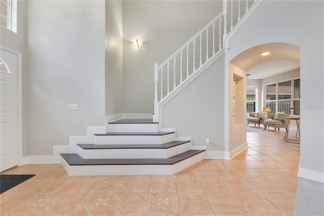 4993 Hook Hollow Cir, Orlando, FL 32837 - stairway featuring a towering ceiling, tile patterned floors, arched walkways, baseboards, and plenty of natural light