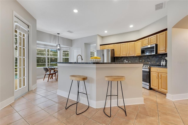 4993 Hook Hollow Cir, Orlando, FL 32837 - kitchen with stainless steel appliances, backsplash, a kitchen bar, light tile patterned flooring, and recessed lighting