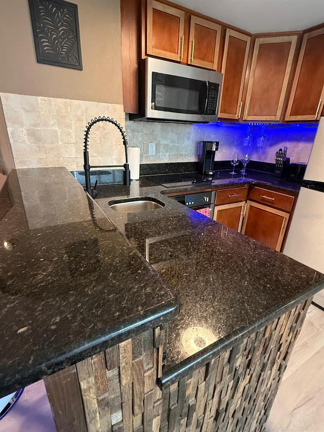 6165 Carrier Dr Unit 1801, Orlando, FL 32819 - kitchen featuring stainless steel microwave, a sink, brown cabinetry, and backsplash