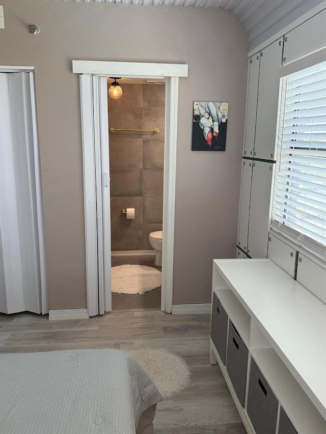 6165 Carrier Dr Unit 1801, Orlando, FL 32819 - bedroom featuring baseboards, light wood-style flooring, and ensuite bathroom