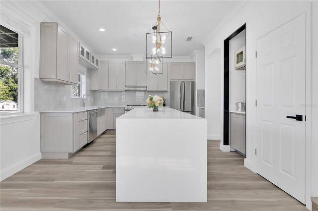 17657 Windy Pine St, Montverde, FL 34756 - kitchen featuring stainless steel appliances, under cabinet range hood, baseboards, ornamental molding, and backsplash