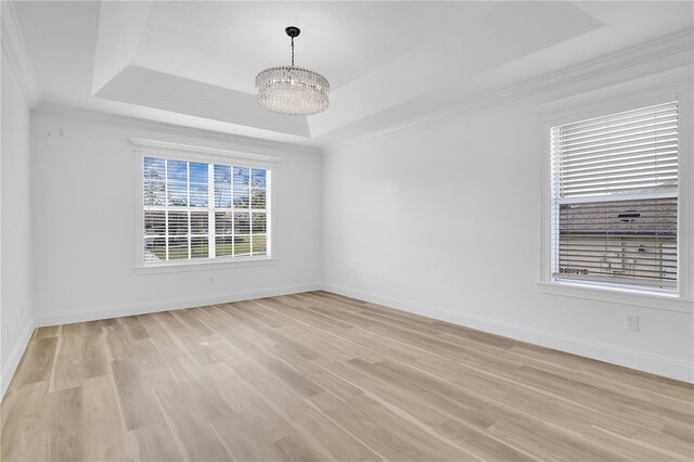 17657 Windy Pine St, Montverde, FL 34756 - empty room featuring a tray ceiling, light wood-type flooring, baseboards, a chandelier, and ornamental molding
