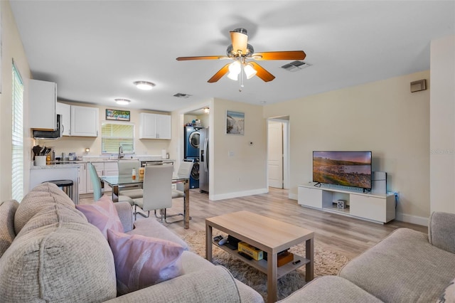 500 W Oakland Ave, Oakland, FL 34760 - living room with stacked washer / dryer, light wood-type flooring, ceiling fan, and baseboards
