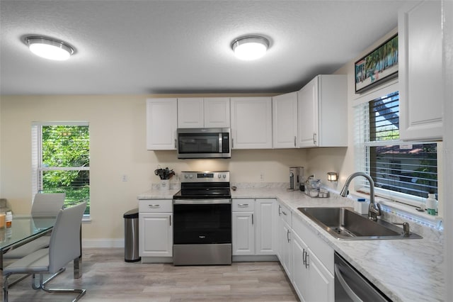 500 W Oakland Ave, Oakland, FL 34760 - kitchen with appliances with stainless steel finishes, a sink, light wood-style flooring, white cabinets, and healthy amount of natural light