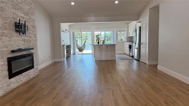 6428 Lynn Rd, Orlando, FL 32810 - unfurnished living room featuring dark wood-type flooring, baseboards, a stone fireplace, and recessed lighting