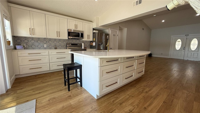 6428 Lynn Rd, Orlando, FL 32810 - kitchen featuring appliances with stainless steel finishes, lofted ceiling, backsplash, white cabinets, and light countertops