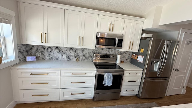 6428 Lynn Rd, Orlando, FL 32810 - kitchen with appliances with stainless steel finishes, light countertops, white cabinetry, dark wood-style floors, and a textured ceiling