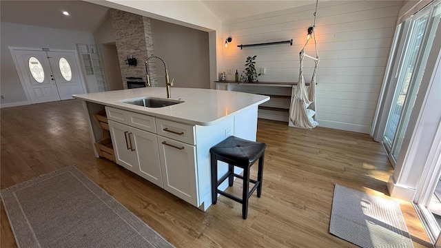6428 Lynn Rd, Orlando, FL 32810 - kitchen featuring a sink, lofted ceiling, light wood finished floors, healthy amount of natural light, and white cabinetry