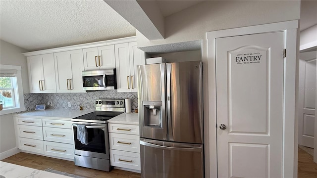 6428 Lynn Rd, Orlando, FL 32810 - kitchen featuring appliances with stainless steel finishes, light countertops, backsplash, white cabinetry, and wood finished floors
