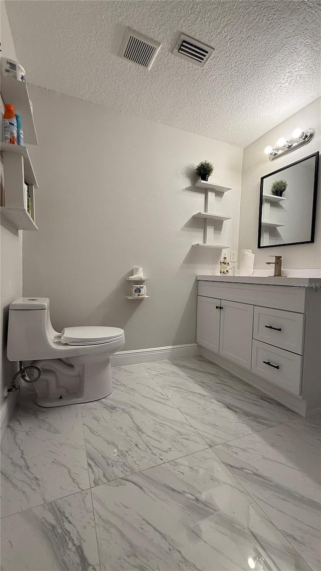 6428 Lynn Rd, Orlando, FL 32810 - bathroom with baseboards, toilet, vanity, marble look tiles, and a textured ceiling