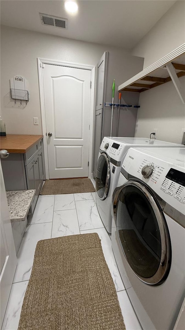 6428 Lynn Rd, Orlando, FL 32810 - laundry room featuring washing machine and dryer, light marble finish flooring, and cabinet space