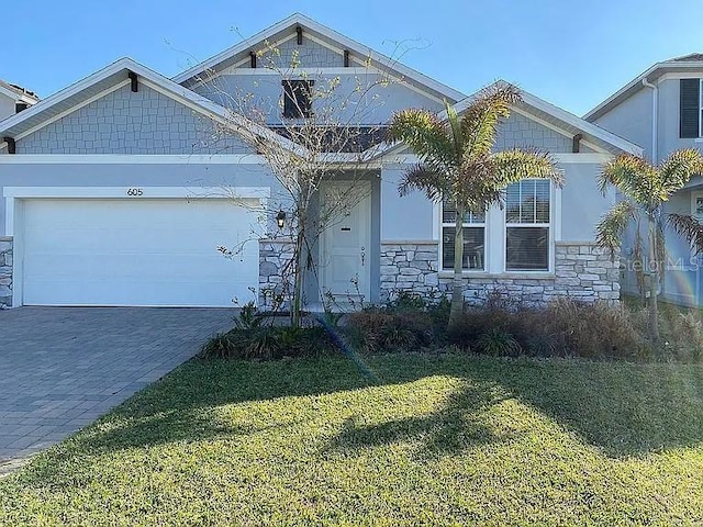 605 Big Pine Ave, Minneola, FL 34715 - view of front of home featuring stone siding, a garage, a front yard, and driveway
