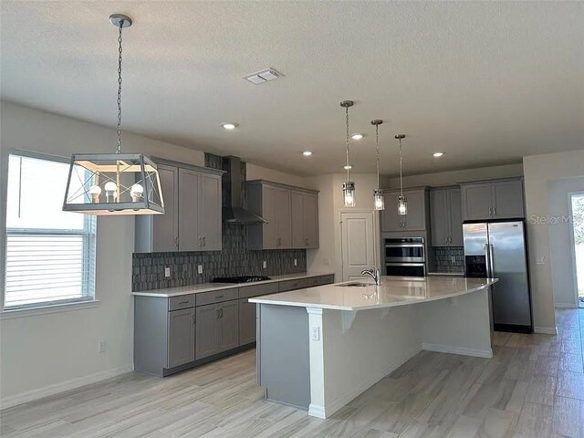 605 Big Pine Ave, Minneola, FL 34715 - kitchen with gray cabinetry, wall chimney exhaust hood, stainless steel appliances, tasteful backsplash, and recessed lighting
