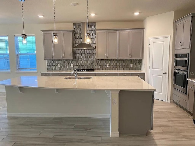 605 Big Pine Ave, Minneola, FL 34715 - kitchen featuring wall chimney range hood, gray cabinets, a sink, stainless steel double oven, and a kitchen bar