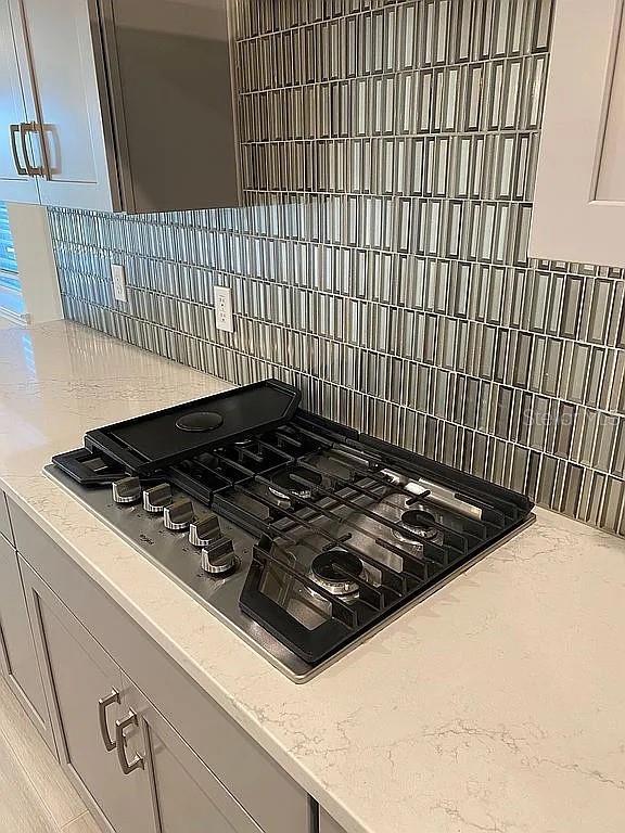 605 Big Pine Ave, Minneola, FL 34715 - kitchen view of stainless steel gas cooktop, backsplash, and light stone counters