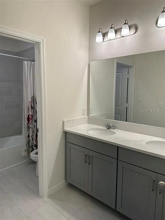 605 Big Pine Ave, Minneola, FL 34715 - bathroom featuring double vanity, tile patterned floors, shower / bath combo with shower curtain, toilet, and baseboards