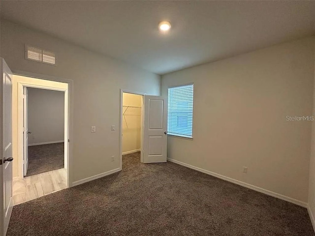 605 Big Pine Ave, Minneola, FL 34715 - unfurnished bedroom with carpet flooring, baseboards, a walk in closet, and a closet