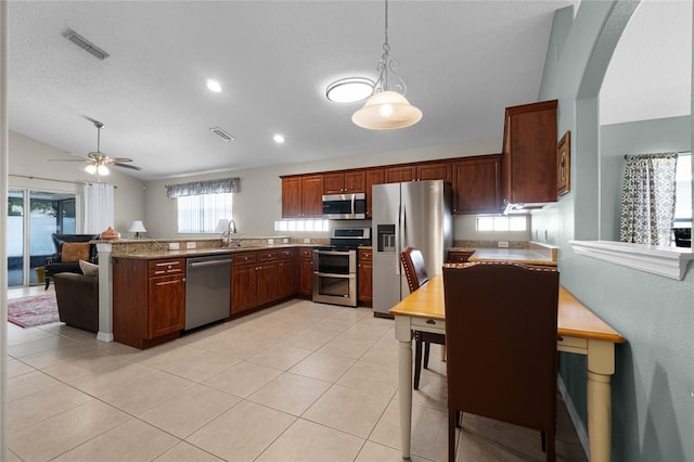 2729 Stanwood Dr, Kissimmee, FL 34743 - kitchen featuring stainless steel appliances, a peninsula, lofted ceiling, light tile patterned floors, and pendant lighting