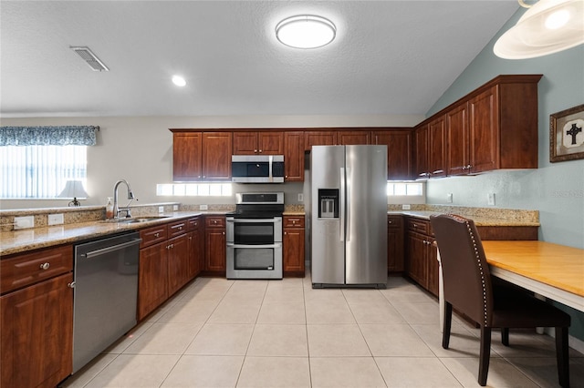2729 Stanwood Dr, Kissimmee, FL 34743 - kitchen featuring stainless steel appliances, a sink, plenty of natural light, light stone countertops, and vaulted ceiling