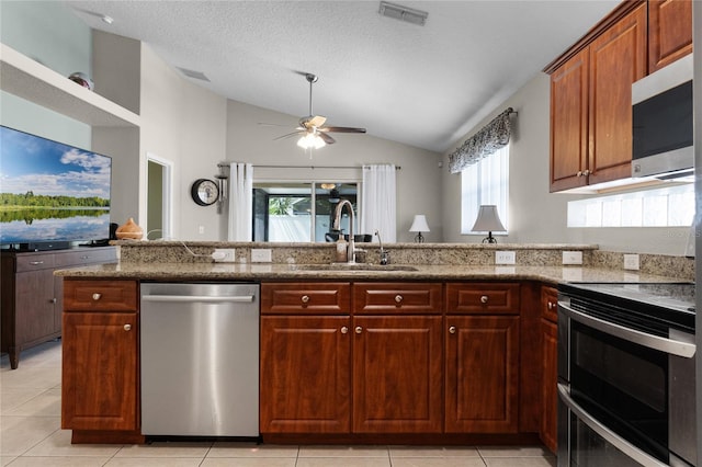 2729 Stanwood Dr, Kissimmee, FL 34743 - kitchen featuring appliances with stainless steel finishes, a sink, vaulted ceiling, ceiling fan, and stone countertops