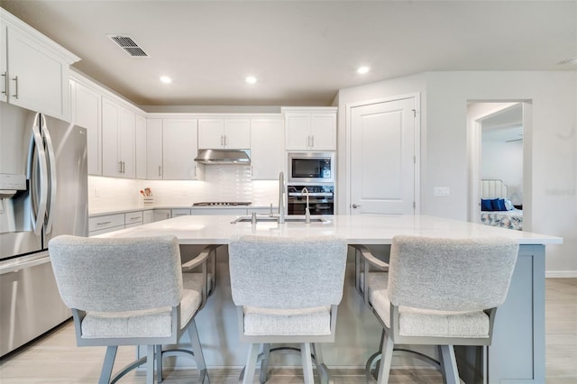 2479 Pine Preserve Ct, Saint Cloud, FL 34771 - kitchen with stainless steel appliances, under cabinet range hood, a sink, tasteful backsplash, and white cabinets