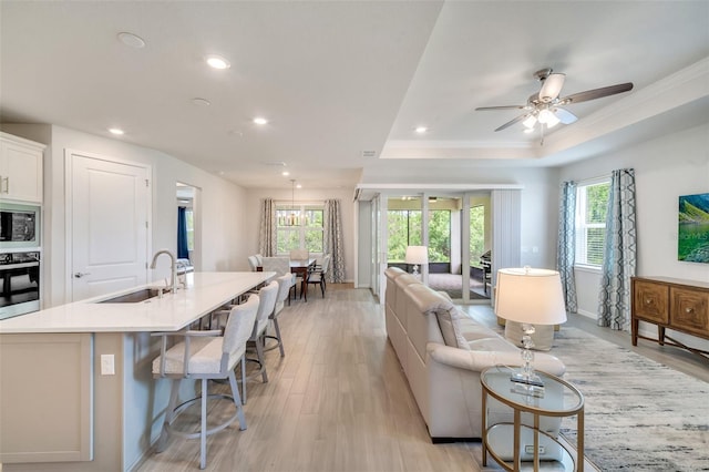 2479 Pine Preserve Ct, Saint Cloud, FL 34771 - living room with light wood-style floors, recessed lighting, a tray ceiling, crown molding, and baseboards