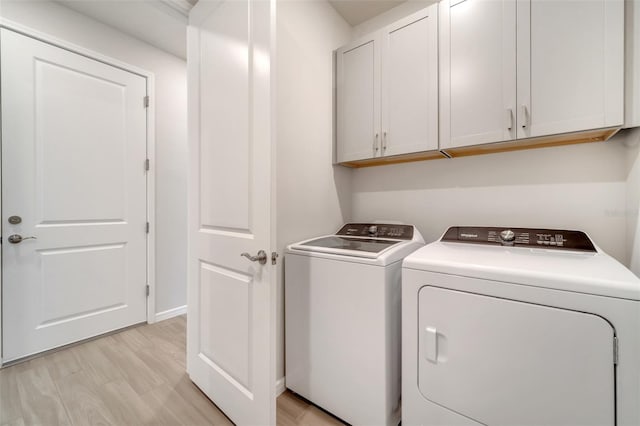 2479 Pine Preserve Ct, Saint Cloud, FL 34771 - laundry area with cabinet space, washer and clothes dryer, light wood finished floors, and baseboards