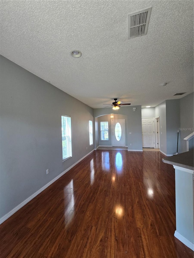 1754 Fritwell Ct, Ocoee, FL 34761 - unfurnished living room featuring a textured ceiling, dark wood-style floors, a ceiling fan, and baseboards