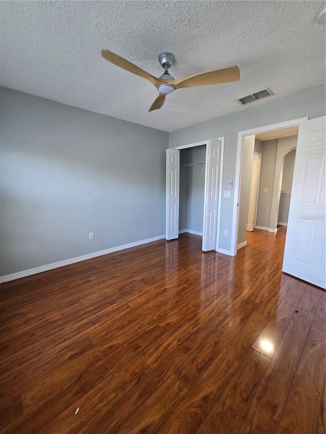 1754 Fritwell Ct, Ocoee, FL 34761 - unfurnished bedroom with wood finished floors, a textured ceiling, baseboards, arched walkways, and a closet