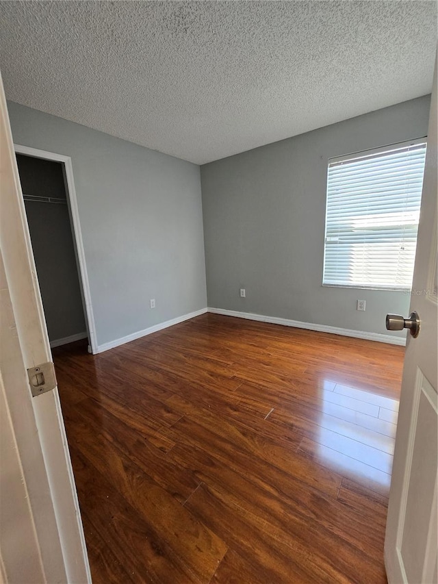 1754 Fritwell Ct, Ocoee, FL 34761 - unfurnished bedroom with wood finished floors, a textured ceiling, and baseboards