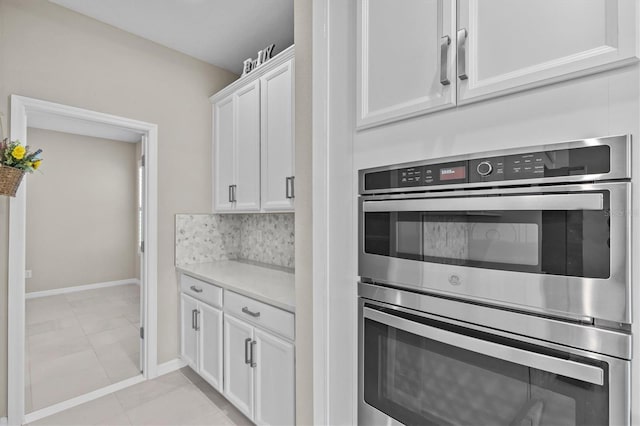 10516 Tranquil Meadow Loop, Riverview, FL 33569 - kitchen featuring stainless steel double oven, white cabinetry, light countertops, light tile patterned floors, and baseboards