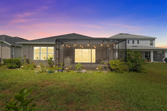 10516 Tranquil Meadow Loop, Riverview, FL 33569 - back of house at dusk with a lawn, stucco siding, a lanai, and a patio area