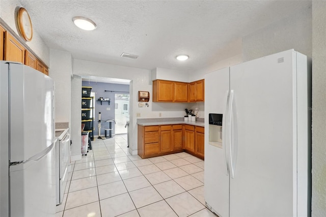 1111 Liberty Ave, Mount Dora, FL 32757 - kitchen with white refrigerator with ice dispenser, freestanding refrigerator, brown cabinetry, light countertops, and light tile patterned flooring