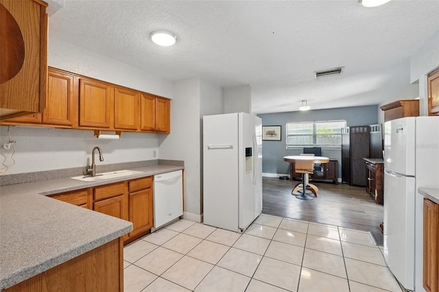 1111 Liberty Ave, Mount Dora, FL 32757 - kitchen featuring white appliances, a sink, brown cabinetry, light countertops, and a textured ceiling