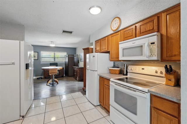 1111 Liberty Ave, Mount Dora, FL 32757 - kitchen featuring white appliances, brown cabinets, light tile patterned floors, a textured ceiling, and light countertops
