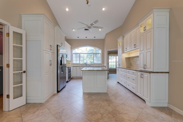 1947 Broadleaf Ct, Windermere, FL 34786 - kitchen featuring appliances with stainless steel finishes, a ceiling fan, vaulted ceiling, a center island, and light stone countertops