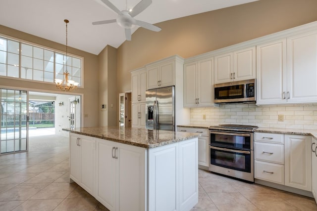 1947 Broadleaf Ct, Windermere, FL 34786 - kitchen with appliances with stainless steel finishes, high vaulted ceiling, a center island, backsplash, and light tile patterned floors