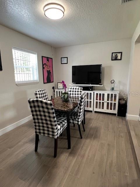 1620 Hialeah St, Orlando, FL 32808 - dining space with a textured ceiling, wood finished floors, and baseboards