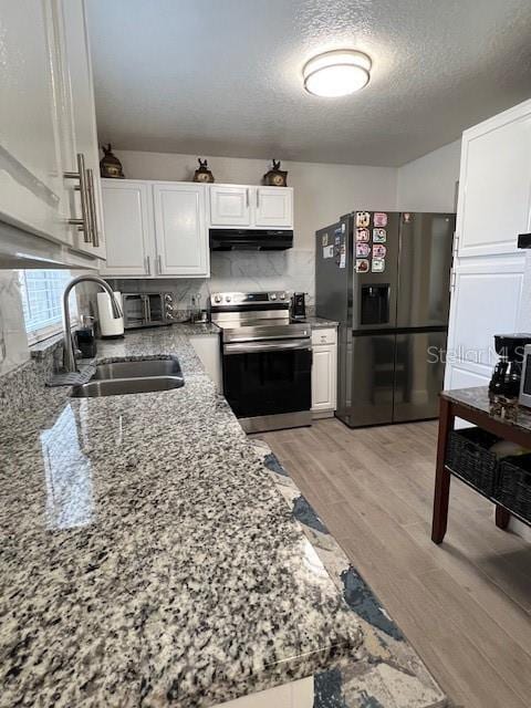 1620 Hialeah St, Orlando, FL 32808 - kitchen with stainless steel electric range oven, refrigerator with ice dispenser, under cabinet range hood, white cabinets, and a textured ceiling