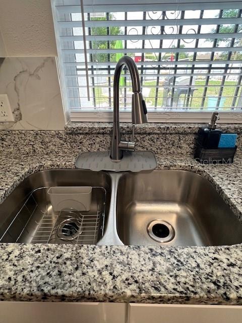 1620 Hialeah St, Orlando, FL 32808 - kitchen view of a sink, light stone countertops, and decorative backsplash