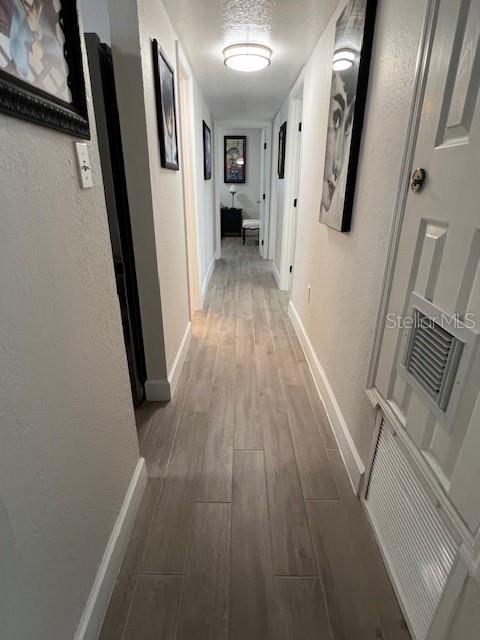 1620 Hialeah St, Orlando, FL 32808 - hallway featuring wood finished floors, baseboards, and a textured wall